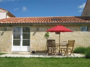 una mesa con 2 sillas y una sombrilla roja en Gîte Auchay-sur-Vendée, 3 pièces, 6 personnes - FR-1-426-96, en Fontenay-le-Comte