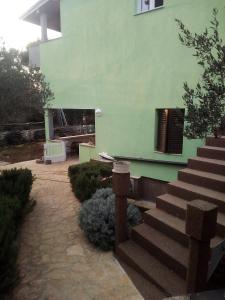 ein grünes Gebäude mit einer Treppe und einem Kamin in der Unterkunft Apartment Silba 17603a in Silba