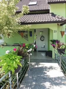 ein grünes Haus mit Blumen an der Haustür in der Unterkunft Apartments and rooms with parking space Slunj, Plitvice - 17719 in Slunj