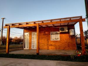 ein kleines Holzhaus mit einer Pergola in der Unterkunft Complejo cabañas el paraje in Ranchos