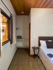 a bedroom with a bed and a table next to a window at Pousada Cipó Cana in Santana do Riacho