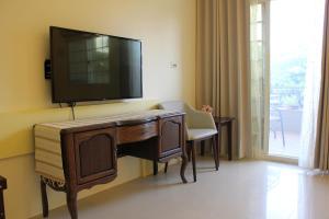 a room with a desk with a television on a wall at Sunny Breeze Garden Homestay in Jiali