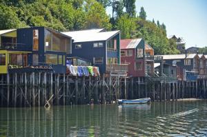 a group of houses on a dock on a body of water at Palafito Verde Apart Hotel in Castro