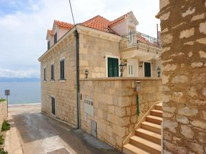 a building with a staircase in front of the ocean at Apartments by the sea Sutivan, Brac - 17796 in Sutivan