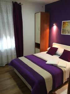 - une chambre dotée d'un lit avec une couverture violette et blanche dans l'établissement Family friendly apartments with a swimming pool Ostarski Stanovi, Plitvice - 17806, à Rakovica