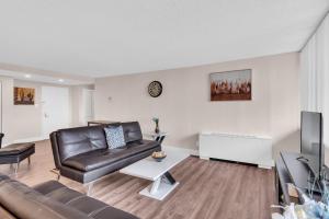 Arlington 2BR 2Ba Apartment in Crystal City apts في أرلينغتون: غرفة معيشة مع أريكة جلدية وتلفزيون