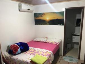 a small bedroom with a bed and a painting on the wall at Pousada Cair do Sol in Ilha do Mel