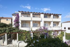 un edificio blanco con flores púrpuras delante de él en Apartment Mavarstica 17821b, en Trogir