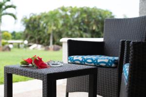 a black wicker chair with a table with flowers on it at Fiji Gateway Hotel in Nadi