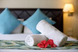 two towels and two red flowers on a bed at Fiji Gateway Hotel in Nadi