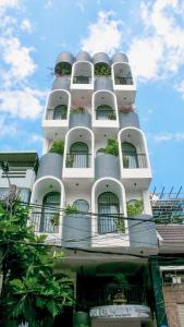 a white building with balconies and plants on it at OH FAMILY QUY NHON HOMESTAY in Quy Nhon