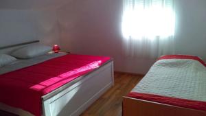 een slaapkamer met een bed met een rode deken en een raam bij Apartments with a parking space Bibinje, Zadar - 17855 in Bibinje