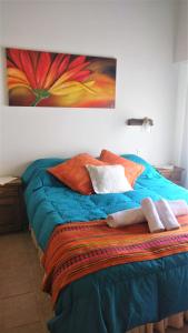 una cama con almohadas y una pintura en la pared en Girasoles Serranos, en Tandil