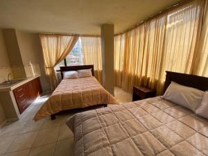 Habitación de hotel con 2 camas y lavamanos en Hostal el Paraíso, en Cuenca