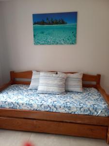 1 cama con 2 almohadas y una pintura en la pared en Residencial Maria Vitoria, en Florianópolis