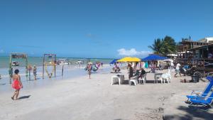 een strand met een groep mensen op het strand bij Flor de Peroba Flats #3 Vermelho - Maragogi - AL in Maragogi