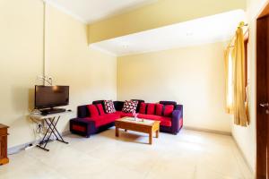 a living room with a red couch and a tv at Sakura Guest House in Canggu