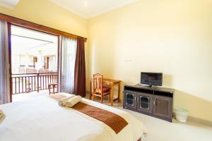 a bedroom with a bed and a television and a balcony at Sakura Guest House in Canggu