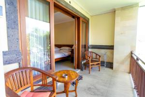 a room with a balcony with a bed and a table and chairs at Sakura Guest House in Canggu
