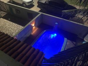 una luz azul en una piscina con coche en Casa com 3 Suites à 200m da Praia - Barra de São Miguel en Barra de São Miguel