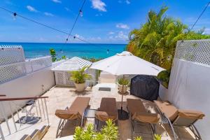 a patio with chairs and an umbrella and the ocean at Bianca Bay 3 Bedroom West Coast Beach Front Villa in Saint James
