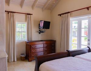 a bedroom with a bed and a dresser and a television at Bianca Bay 3 Bedroom West Coast Beach Front Villa in Saint James