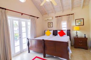Schlafzimmer mit einem Bett mit roten und gelben Kissen in der Unterkunft Bianca Bay 3 Bedroom West Coast Beach Front Villa in Saint James