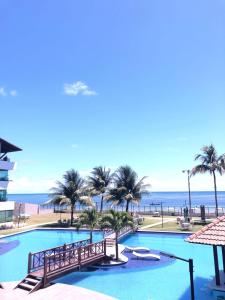 a view of a swimming pool with palm trees and the ocean at Maui - Tamandare - Carneiros in Tamandaré