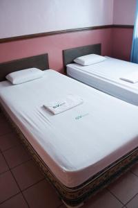 two beds in a room with white sheets and towels at GV Hotel - Maasin in Maasin