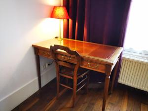a wooden desk with a lamp and a chair at Les Carrés in Versailles