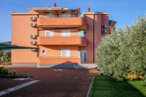 um grande edifício laranja em frente a um parque de estacionamento em Family friendly apartments with a swimming pool Nevidjane, Pasman - 18054 em Neviđane