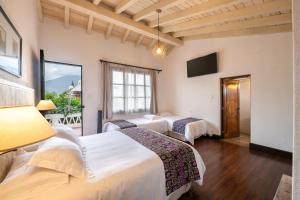 a hotel room with two beds and a television at Barbara's Boutique Hostel in Antigua Guatemala