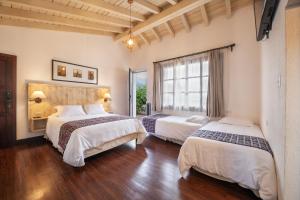 a hotel room with two beds and a window at Barbara's Boutique Hostel in Antigua Guatemala
