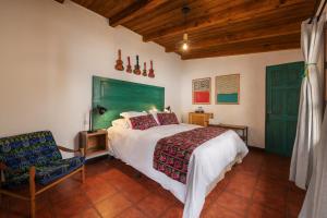 a bedroom with a bed with a green headboard and a chair at Barbara's Boutique Hostel in Antigua Guatemala
