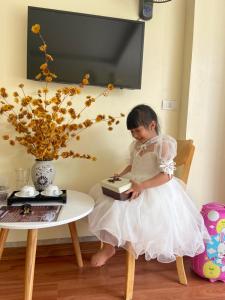 a little girl in a white dress sitting on a chair with a cake at ChiChi Hotel Sapa in Sapa