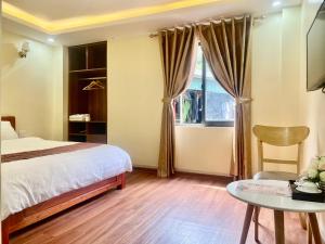 a bedroom with a bed and a table and a window at ChiChi Hotel Sapa in Sapa