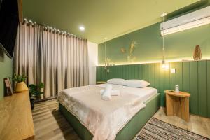 a green bedroom with a bed with two pillows at Apartamentos Go Living & Suites by HOUSY HOST in Medellín