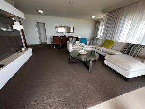 uma sala de estar com um sofá e uma mesa em Darwin Esplanade Central Official em Darwin