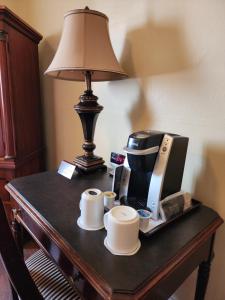 a table with a coffee maker and coffee cups and a lamp at The Faust Hotel in New Braunfels