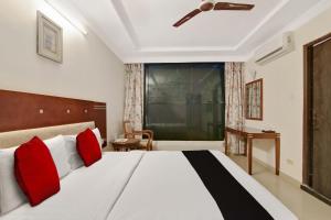 una camera da letto con un grande letto bianco con cuscini rossi di Elegant Amethyst Business Hotel Near Ragigudda Sri Prasanna a Bangalore