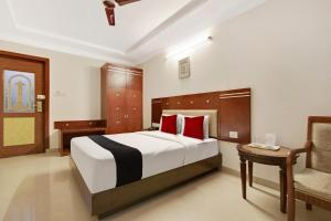 una camera da letto con un letto con cuscini rossi e una sedia di Elegant Amethyst Business Hotel Near Ragigudda Sri Prasanna a Bangalore