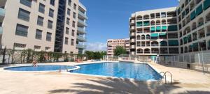 a swimming pool in the middle of two buildings at vacaciones en pineda con 2 piscinas, playa a 5 min in La Pineda