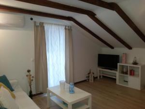 ein Wohnzimmer mit einem weißen Sofa und einem Fernseher in der Unterkunft Apartments by the sea Razanj, Rogoznica - 18089 in Rogoznica