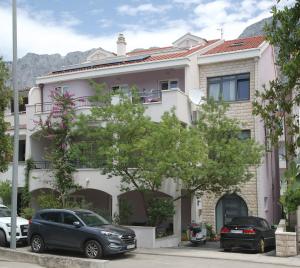 un bâtiment avec des voitures garées devant lui dans l'établissement Apartments and rooms with parking space Makarska - 18106, à Makarska
