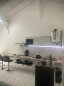 a white kitchen with a black refrigerator and a counter at TRANSIT AFFAIRES - LOISIRS in Pointe-à-Pitre