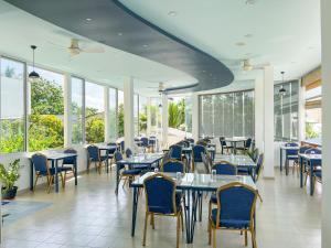 a dining room with tables and chairs and windows at Rehendhi Villa in Maafushi
