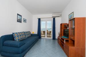 a living room with a blue couch and a television at Apartments by the sea Igrane, Makarska - 18069 in Igrane