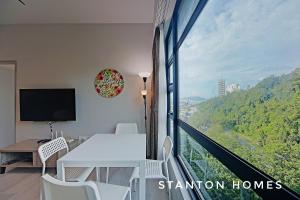 a room with a balcony with a table and a television at Jesselton Quay HOMESTAY by Stanton Homes in Kota Kinabalu