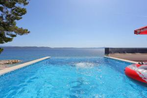 a large swimming pool next to a body of water at Family friendly apartments with a swimming pool Zivogosce - Porat, Makarska - 18150 in Živogošće