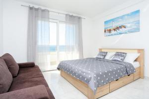 a bedroom with a bed and a couch at Family friendly apartments with a swimming pool Zivogosce - Porat, Makarska - 18150 in Živogošće